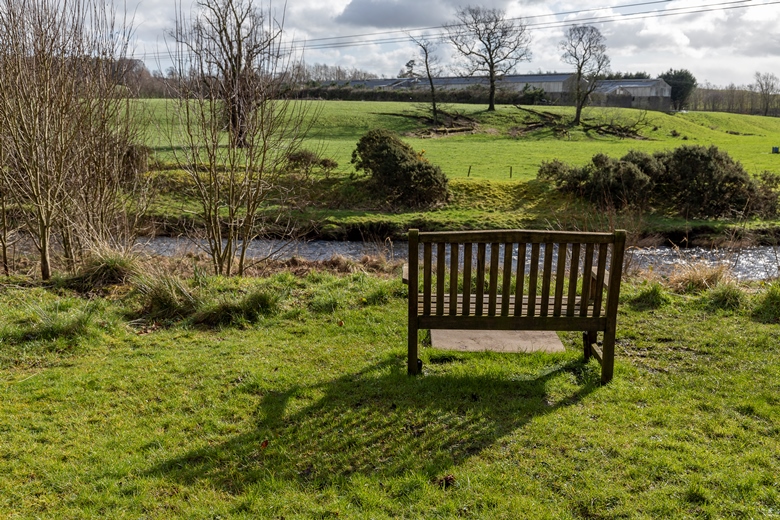 A memorial bench in Lainshaw Woods, overlooking Annick Water. Photo by Cara Smillie.